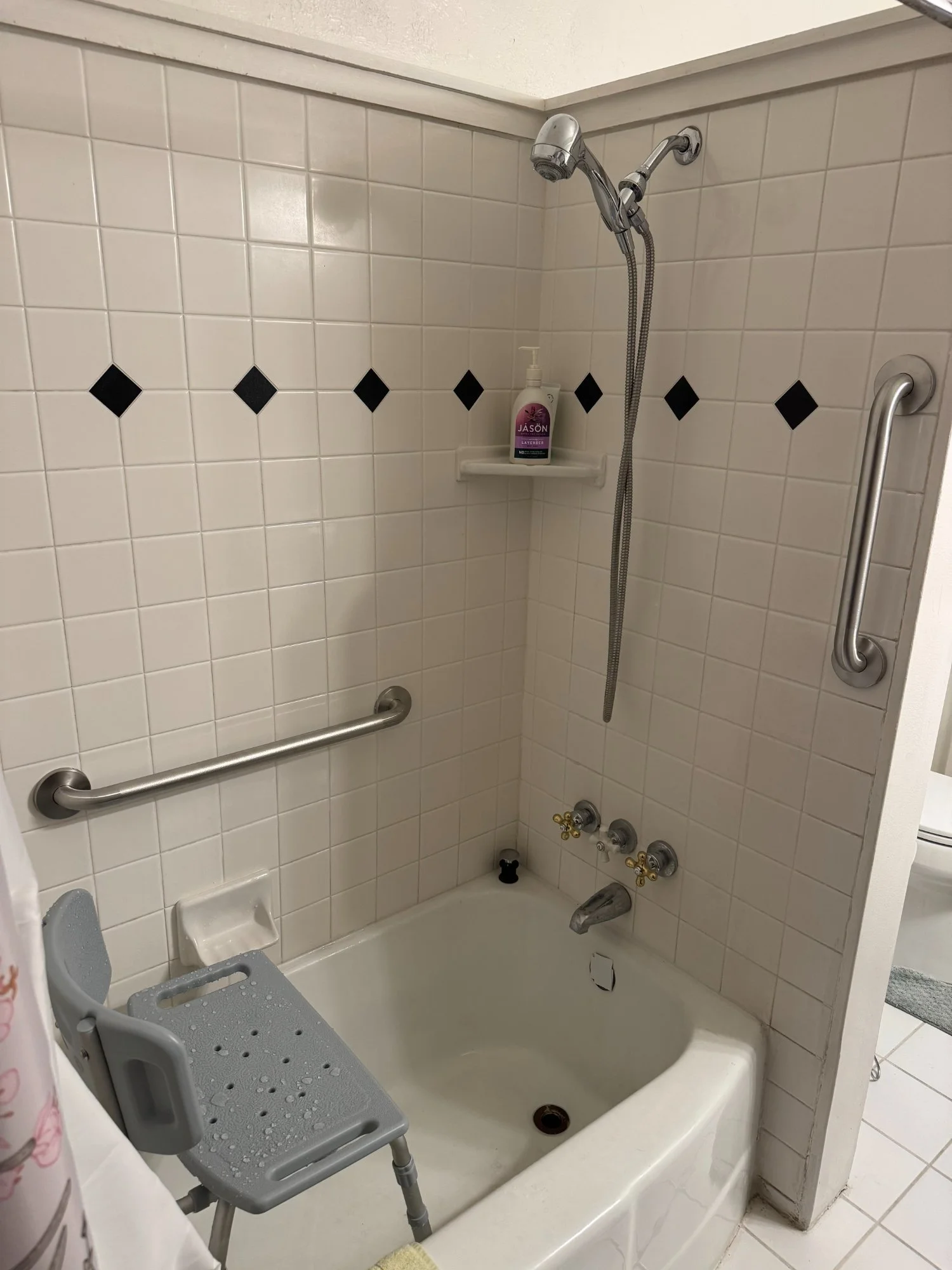 Grab bars installed in tub shower with travertine tile, residential home safety modification