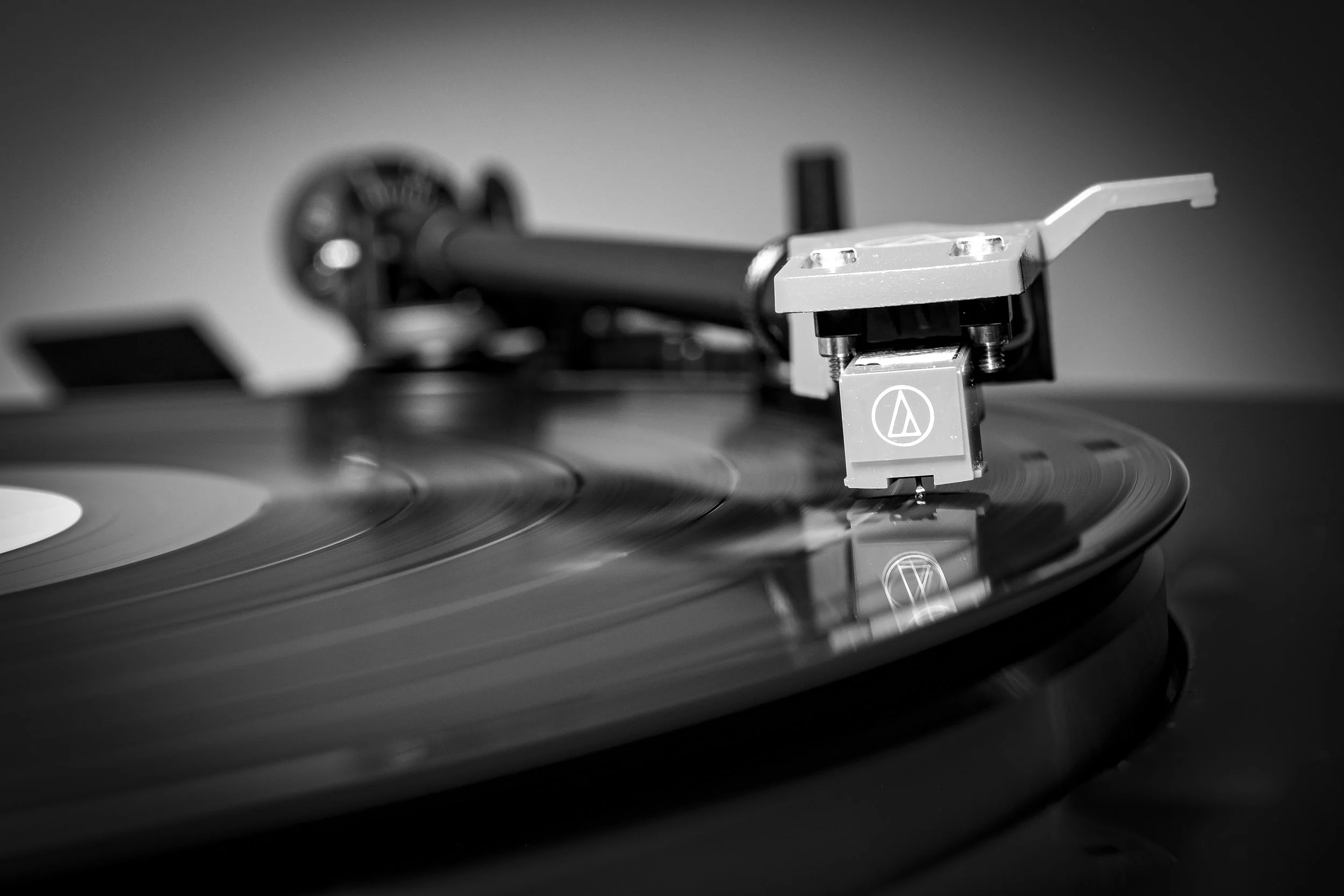 Close-up of a turntable playing a vinyl record in black and white.