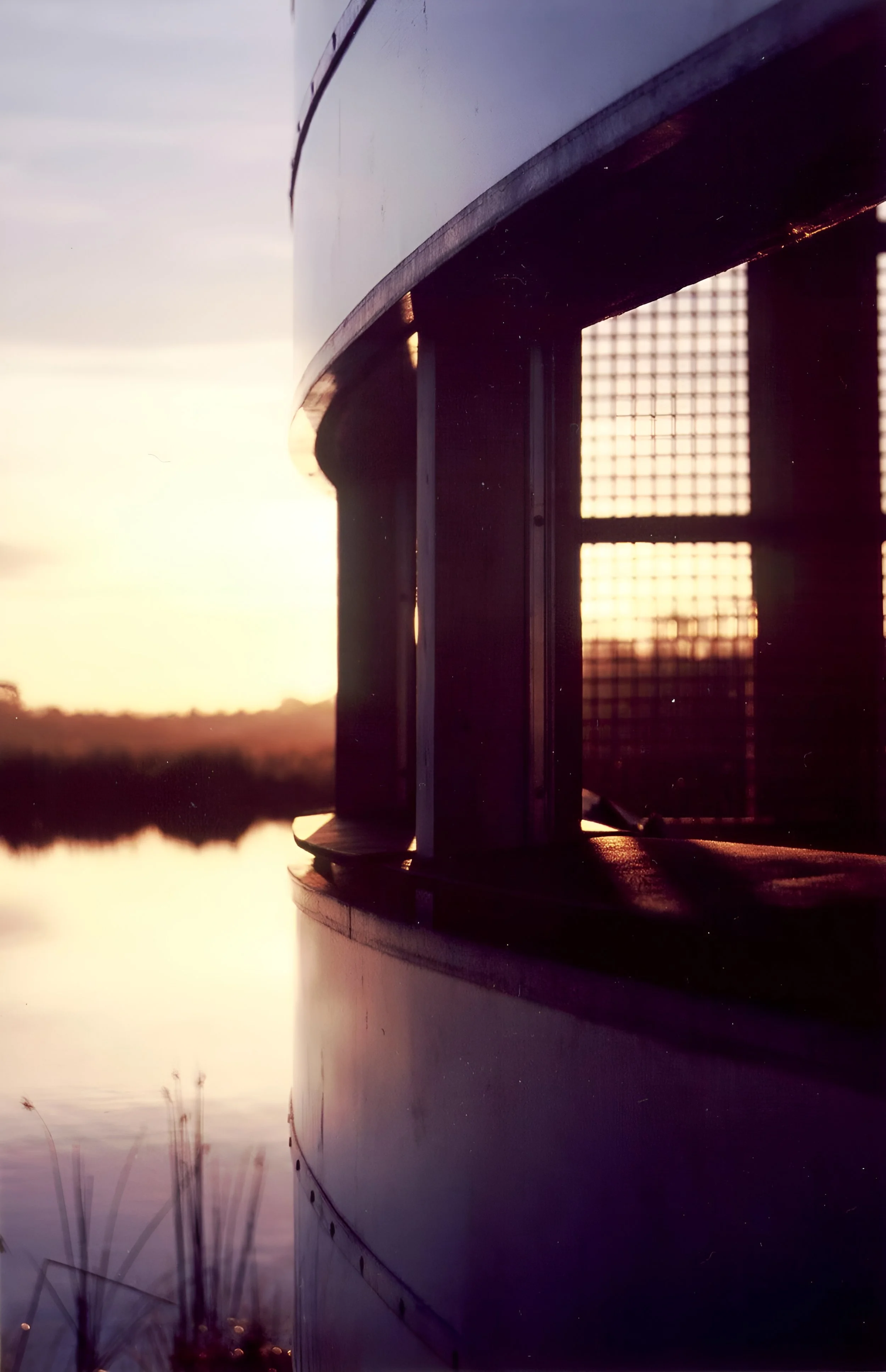 Close-up of a boat or ferry with the sun setting in the background, reflecting on the water.