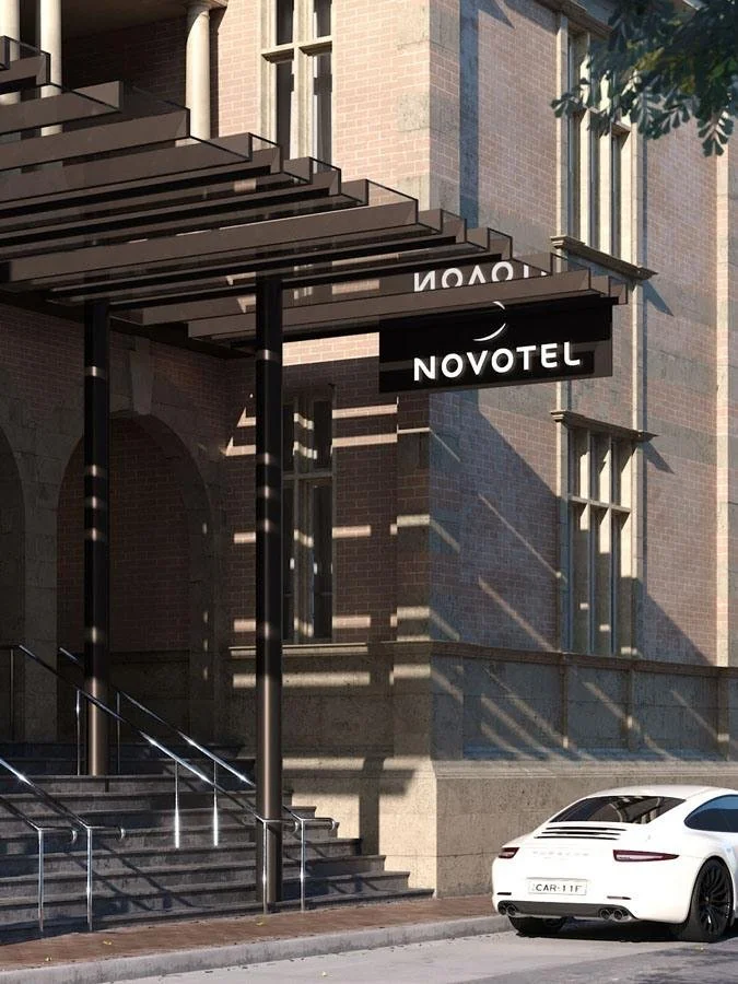 Exterior of a building with a sign for Novotel hotel, showing stairs, black and white exterior, and a white car parked in front.