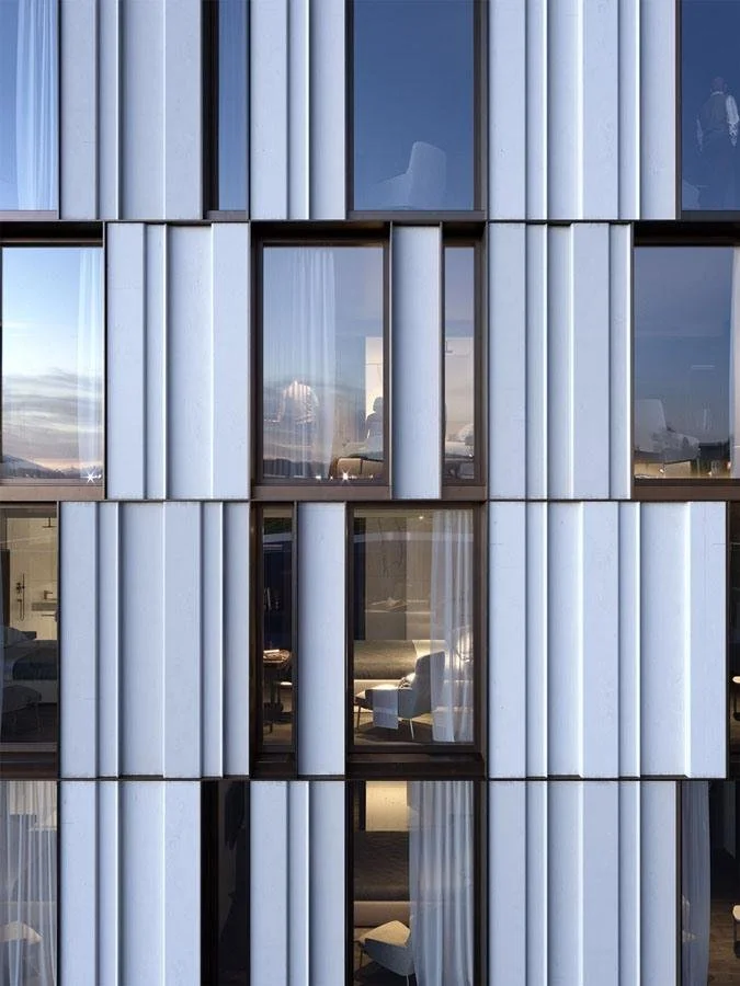 A modern building facade with large glass windows and vertical metal panels arranged in a geometric pattern.