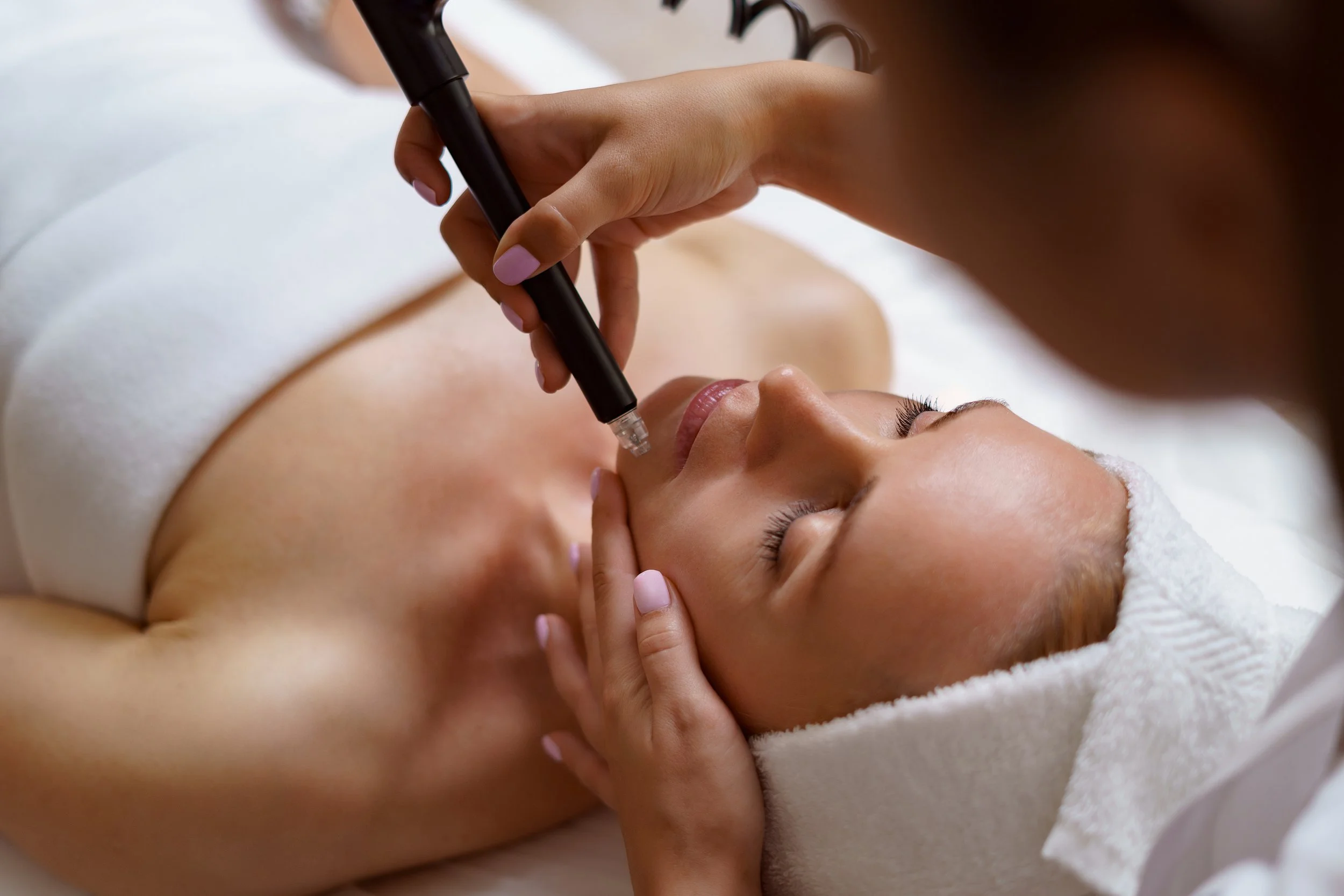 Une femme reçoit un traitement esthétique du visage lors d'un soin dans un spa ou un centre de beauté.