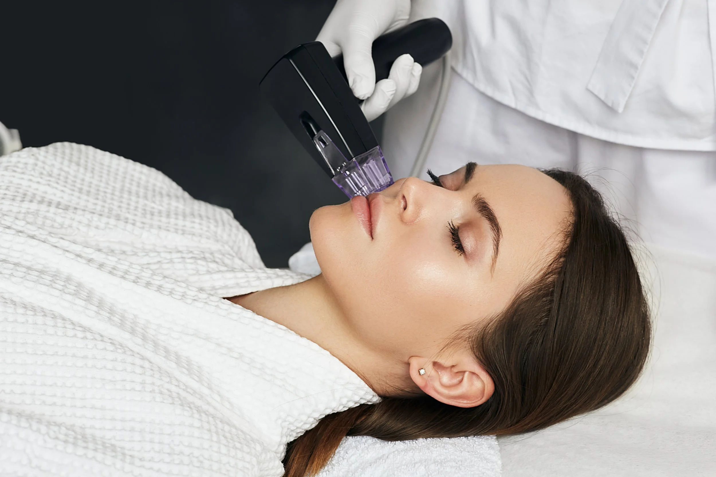 Une femme reçoit un traitement de rajeunissement facial à l'aide d'un appareil médical dans un cabinet de soins esthétiques
