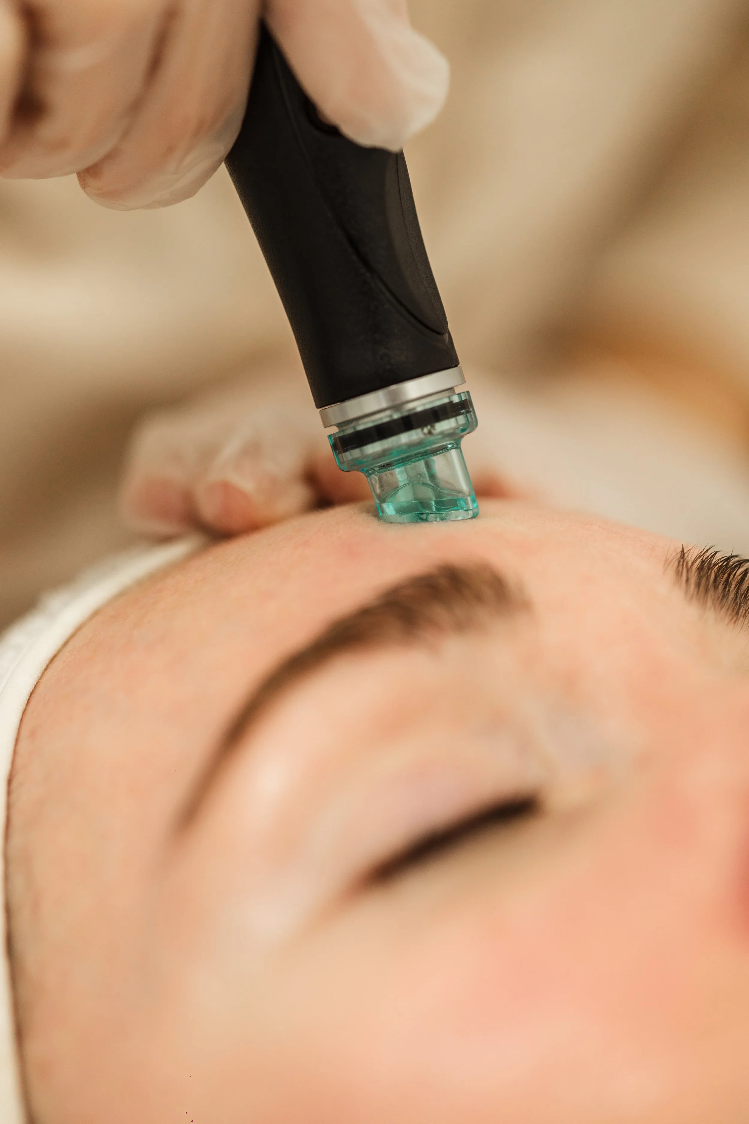 Une esthétique de soin du visage avec un appareil électrique appliqué sur le front d'une personne