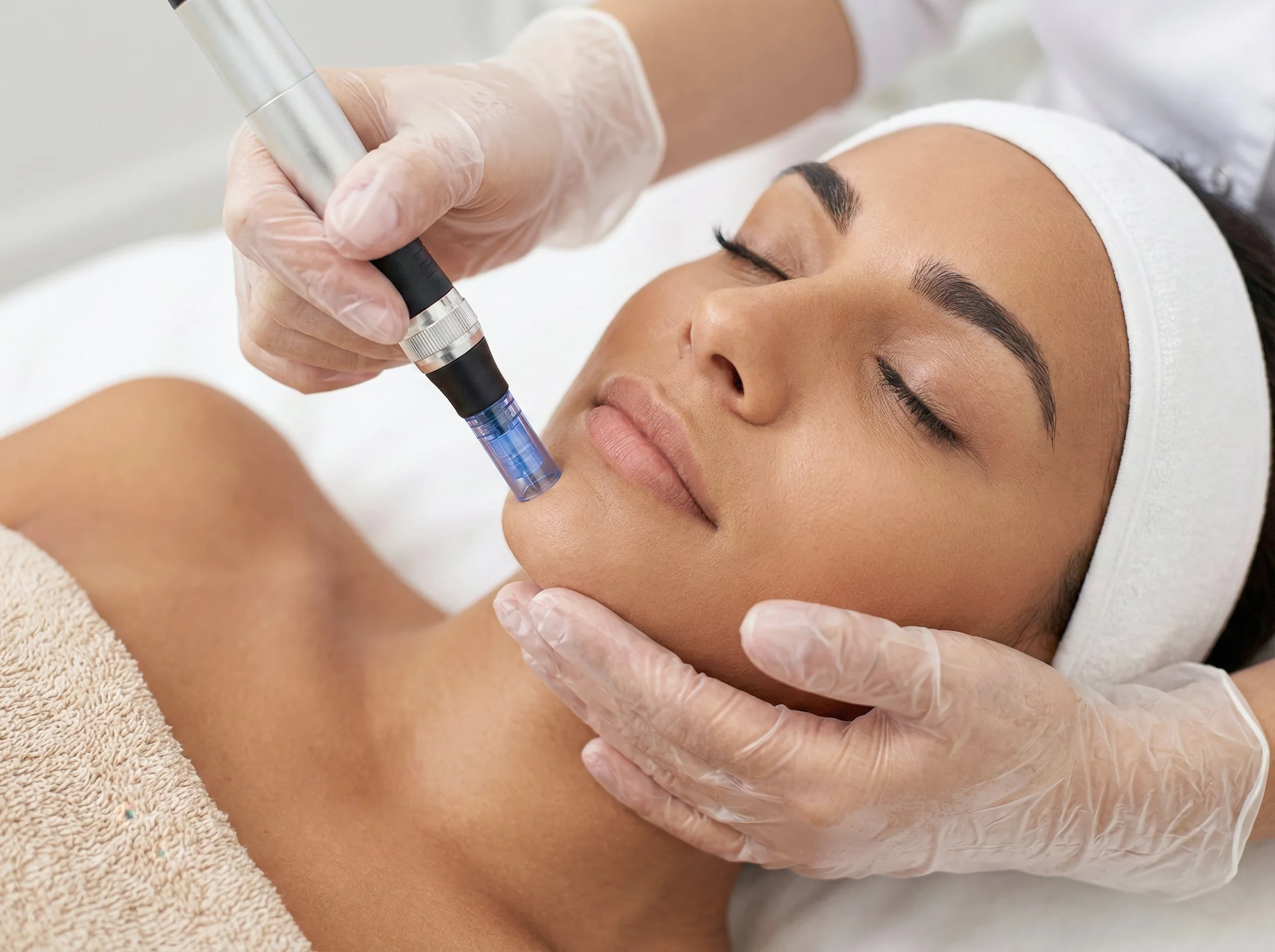 Une femme reçoit un traitement de microdermabrasion sur le visage par un spécialiste portant des gants en plastique dans un centre de soins de peau.