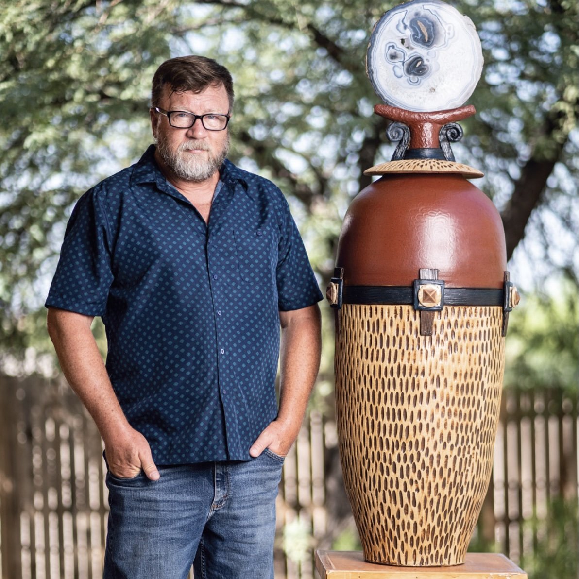 Ceramic artist Myron Whitaker standing beside a large-scale ceramic vessel