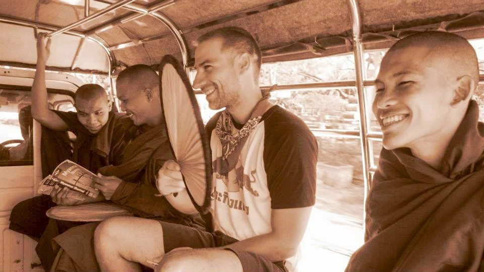 A man with monks in the back of a transport vehicle in Myanmar