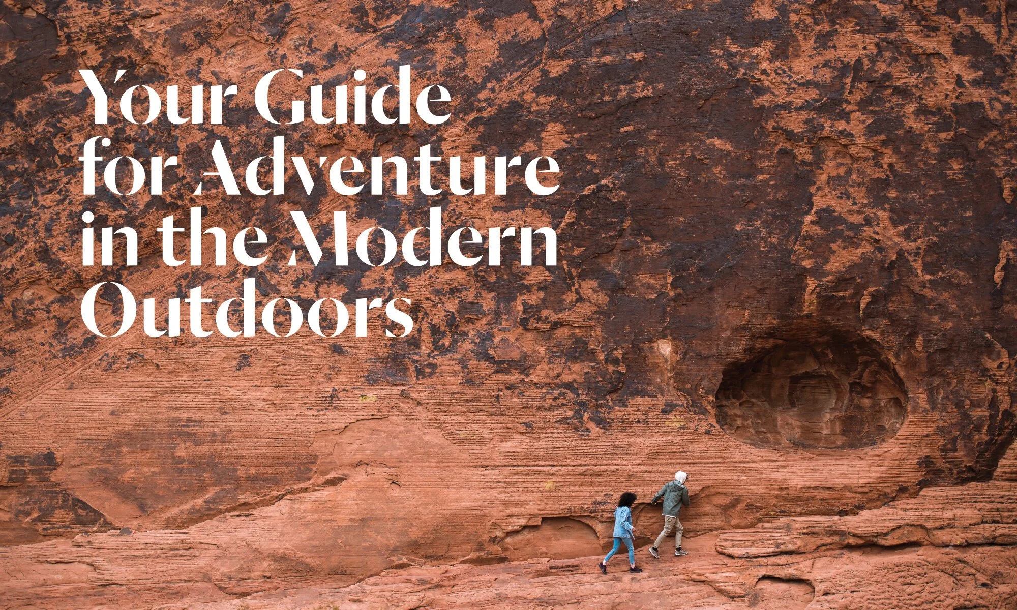 Two hikers walk in front of a desert rock formation with a large, naturally-formed circular hole. Overlaid text reads, "Your Guide for Adventure in the Modern Outdoors."