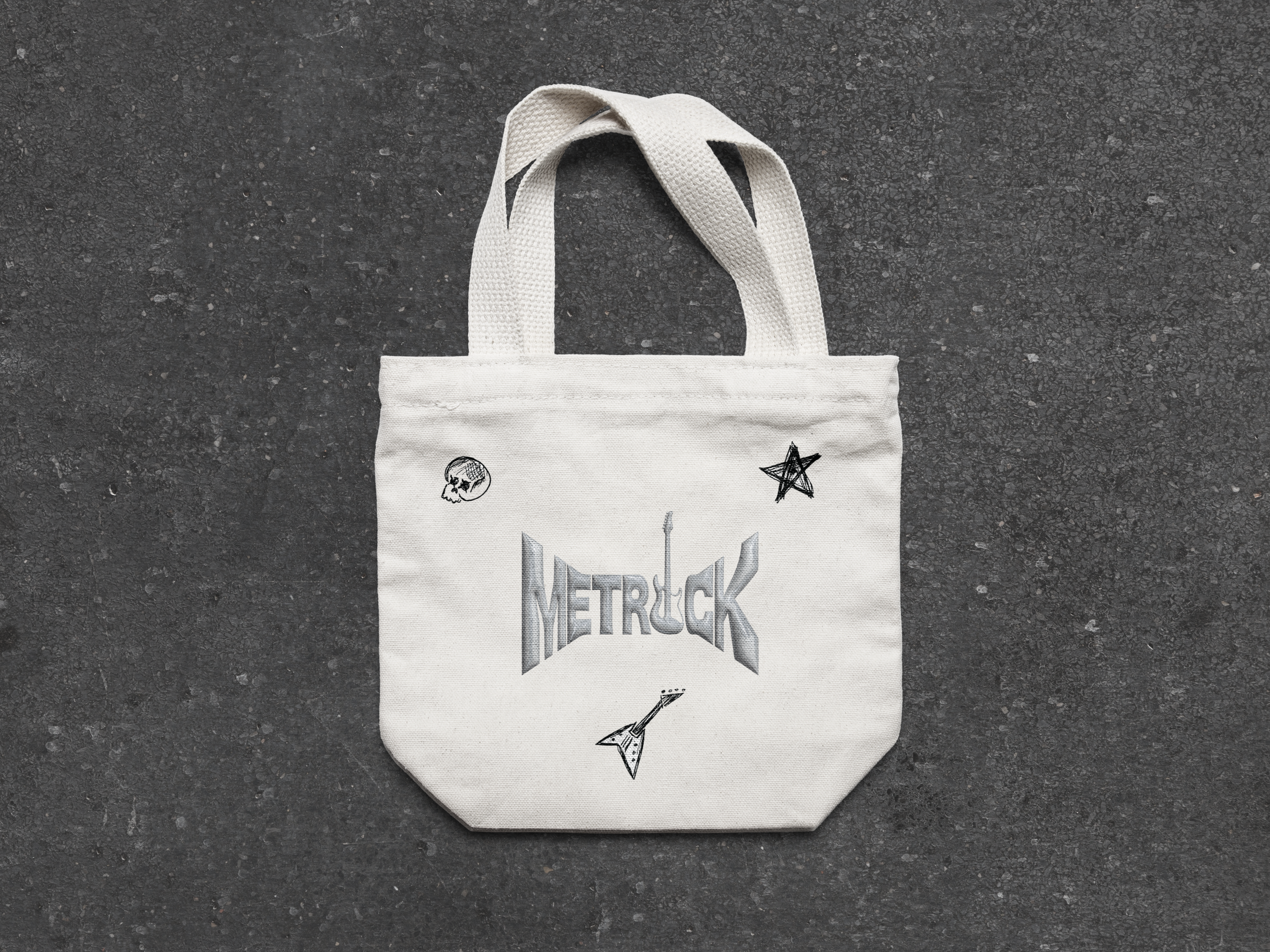 White tote bag with metal truck logo and small doodle-style illustrations of a skull, star, and guitar on a dark textured surface.
