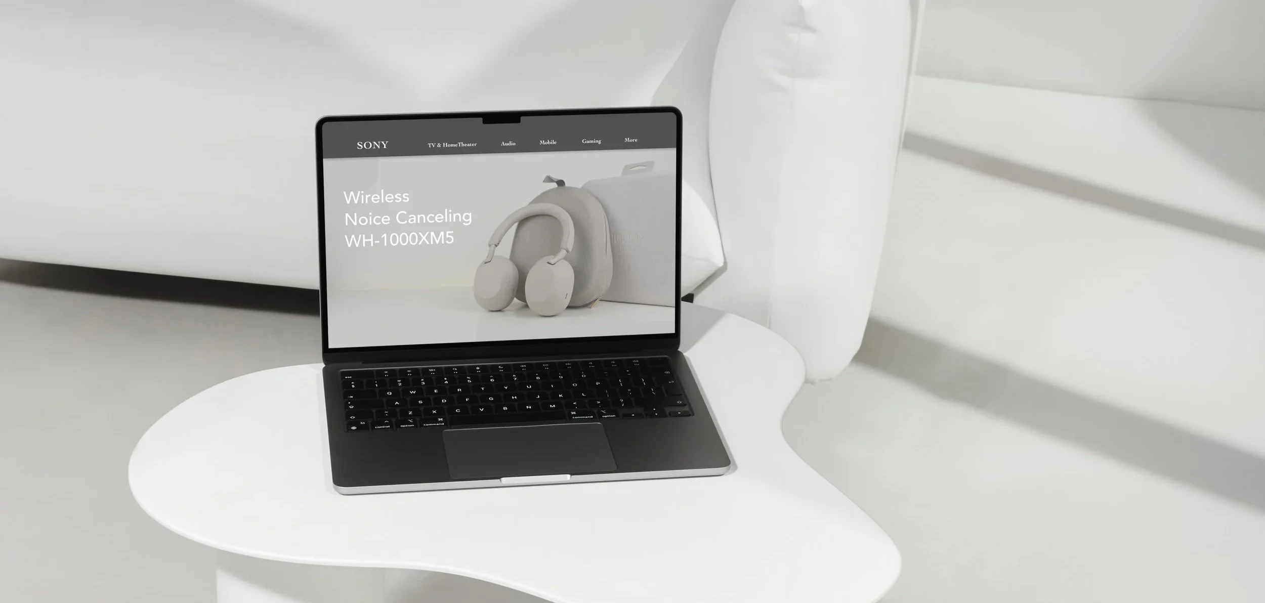 Laptop on a white table displaying a product page for Sony wireless noise cancelling headphones, WH-1000XM5, in a minimalistic, monochrome setting.