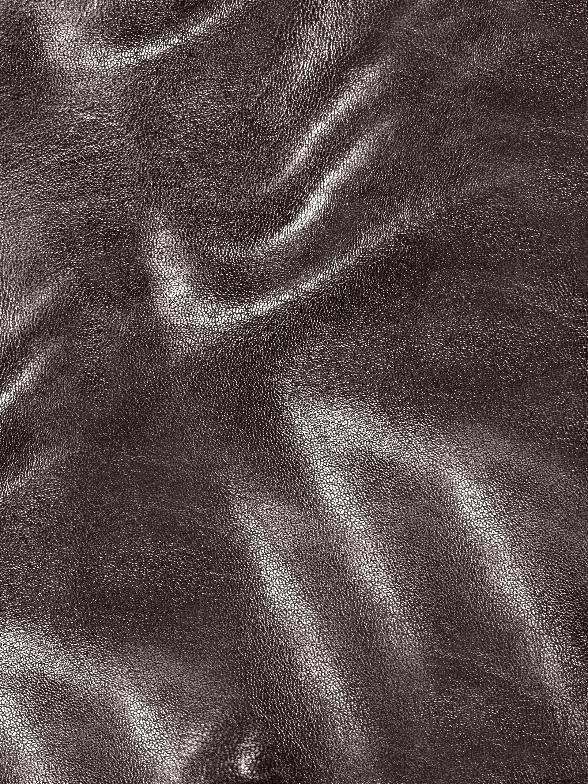 Close-up of a textured, shiny, dark brown leather surface with visible creases and reflections.