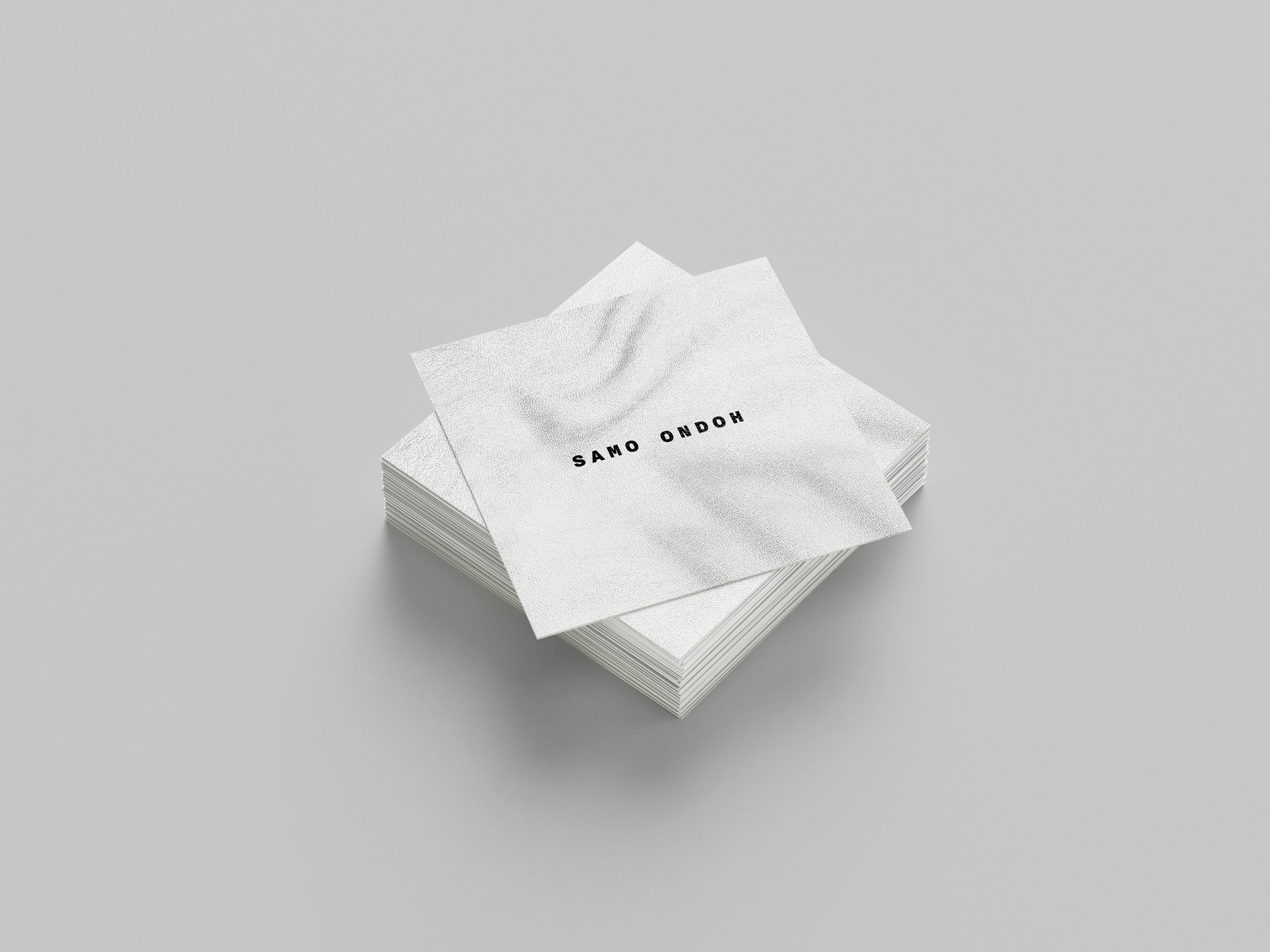 Stack of white paper napkins with black text that reads 'SAMO ONDOH' on the top napkin, on a light grey surface.