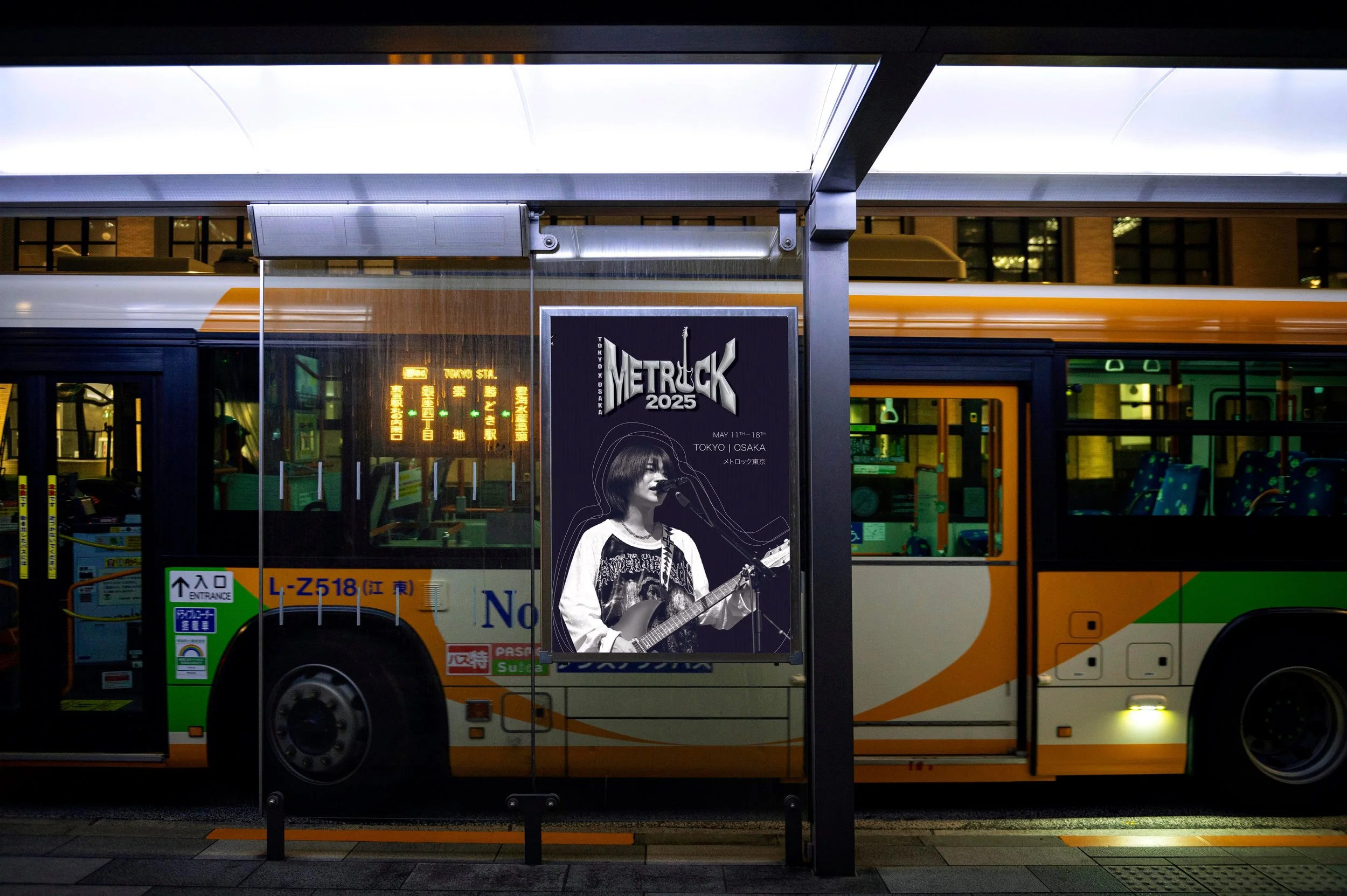 A bus at a bus stop with a poster advertisement for METROCK 2025 music festival in Tokyo and Osaka. The bus has orange, yellow, green, and white colors with windows, and the bus stop has a black pole with a white illuminated roof.