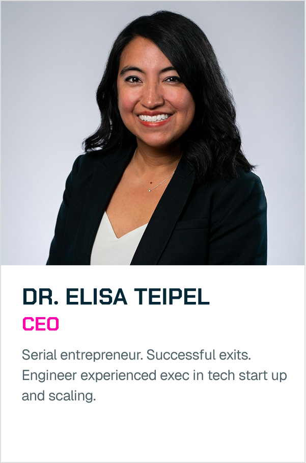 A professional woman with black hair, wearing a black blazer and white top, smiling at the camera against a plain light gray background.