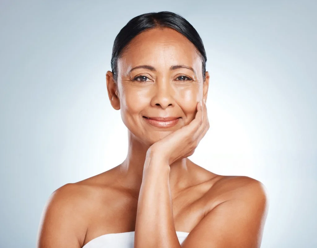 Confident woman touching her face representing surgical dermatology treatments at Isla Dermatology in Key West