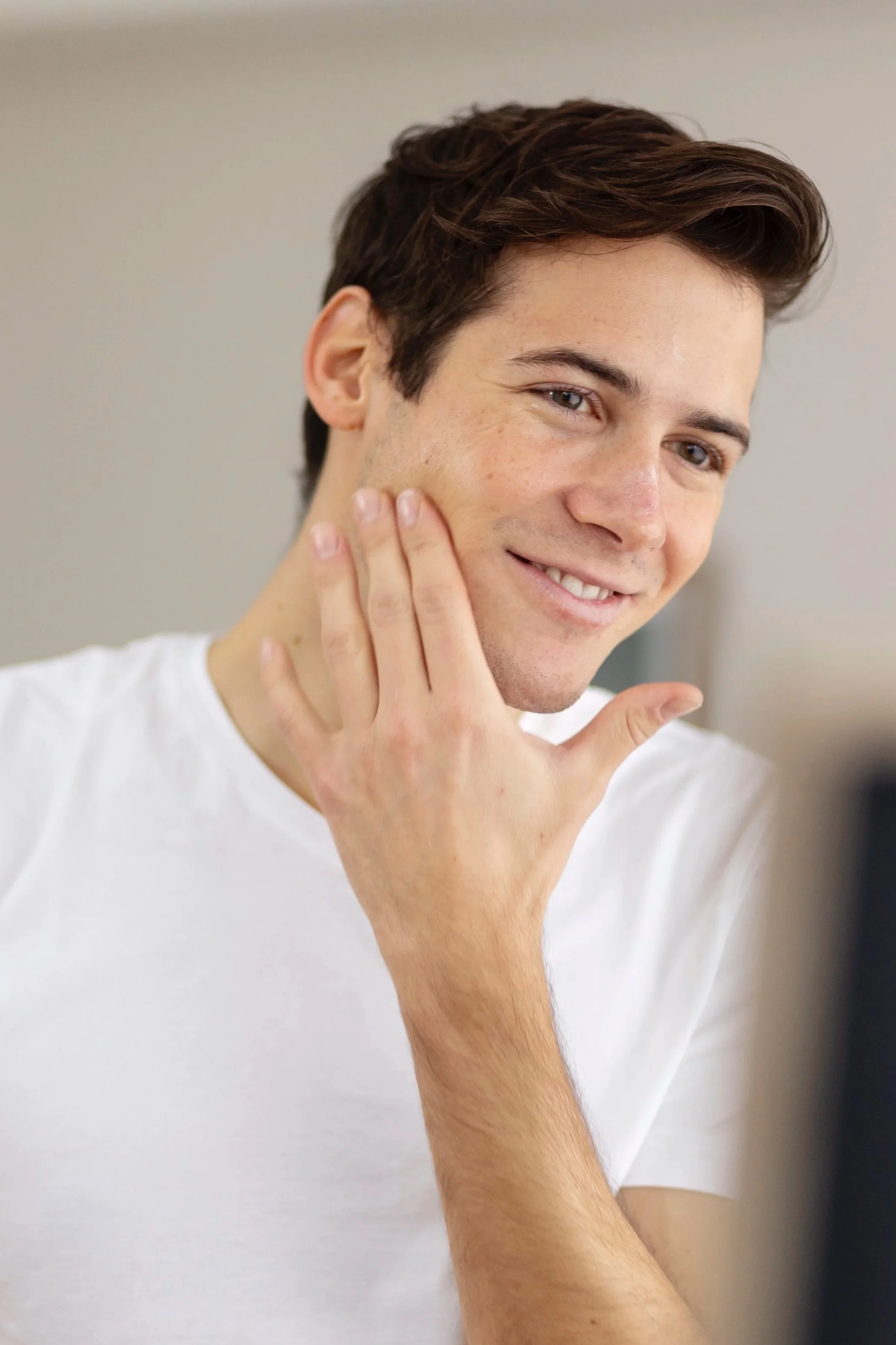 Young man touching his cheek representing laser dermatology treatments at Isla Dermatology in Key West