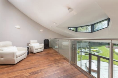 The home features a light-filled living area with a mezzanine level overlooking the lounge, perfect for a home office or reading nook