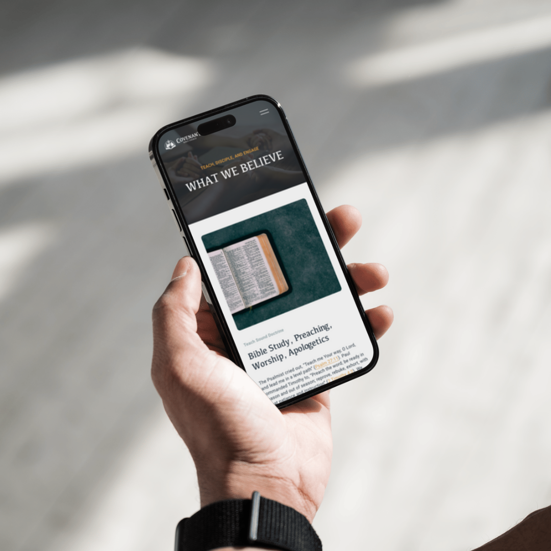 Person holding a smartphone displaying a webpage about Bible study, preaching, worship, and apologetics with an open Bible image on the screen.