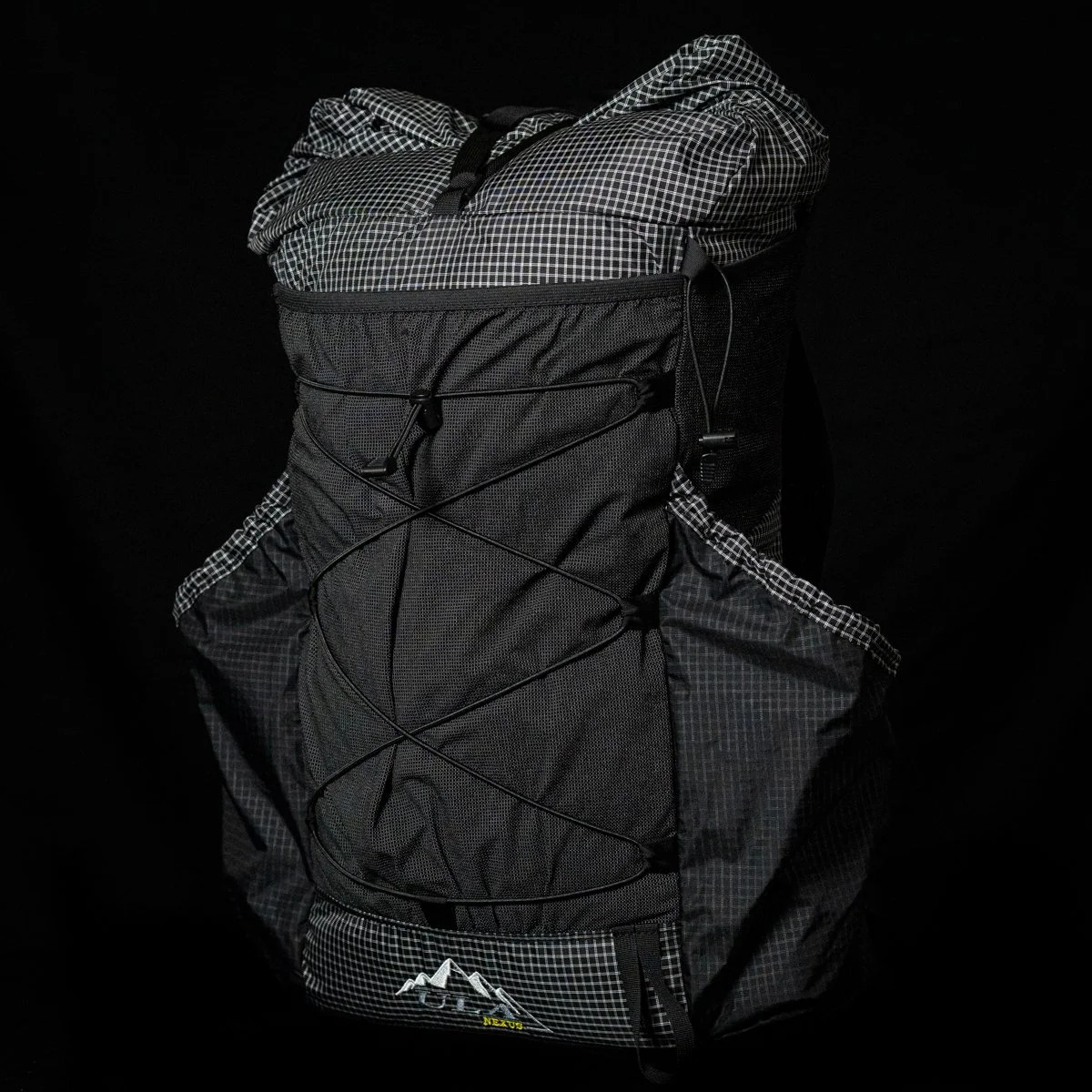 Black and gray backpack with a jacket stuffed inside, set against a black background.