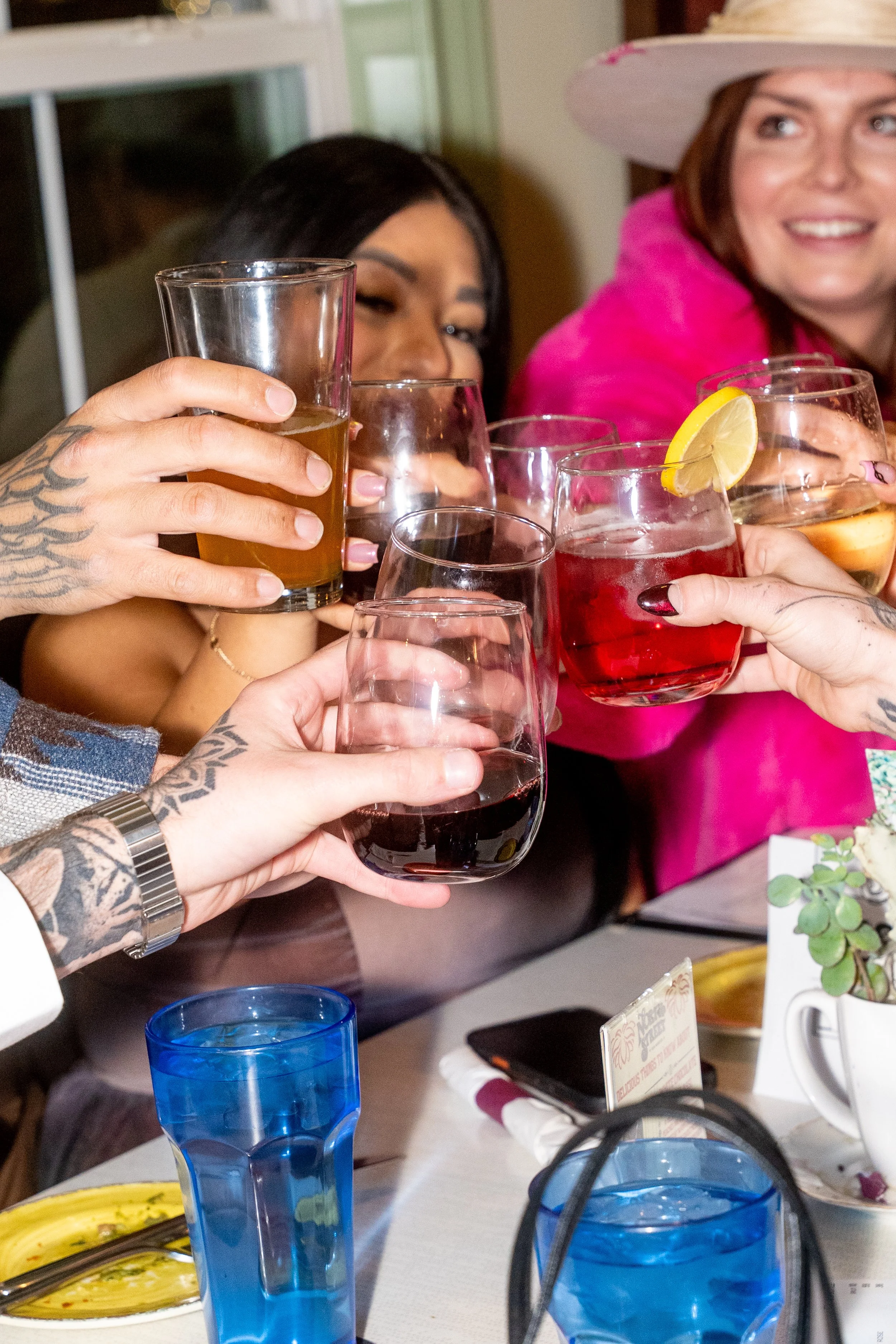 People raising glasses of different drinks in a toast at a social gathering.