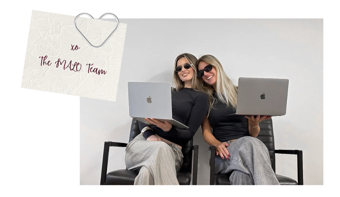 Two women sitting on black chairs, holding MacBook laptops and wearing sunglasses, smiling at the camera, with a white wall background. A note with a heart paperclip says, "xo The MACO Team."