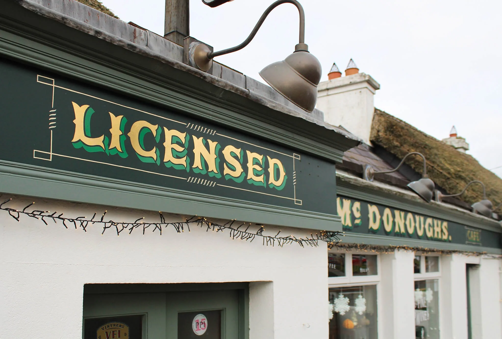 Storefront signwwriting in vintage styled green and beige letters. The background of the sign is dark green with white decorative borders.