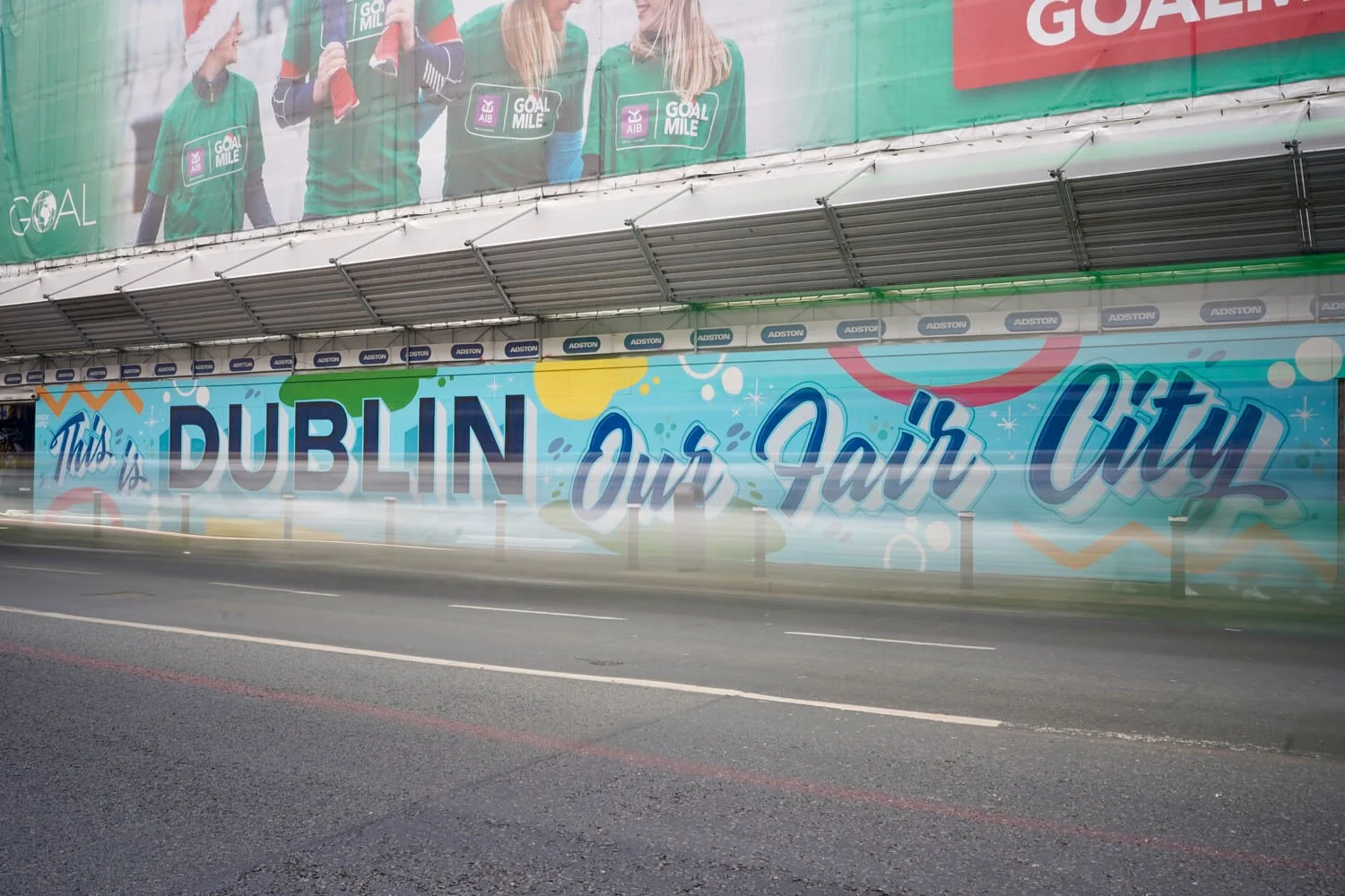 A colorful city mural that reads "This is Dublin Our Fair City" hanging on the side of Dublin's Aviva Stadium.