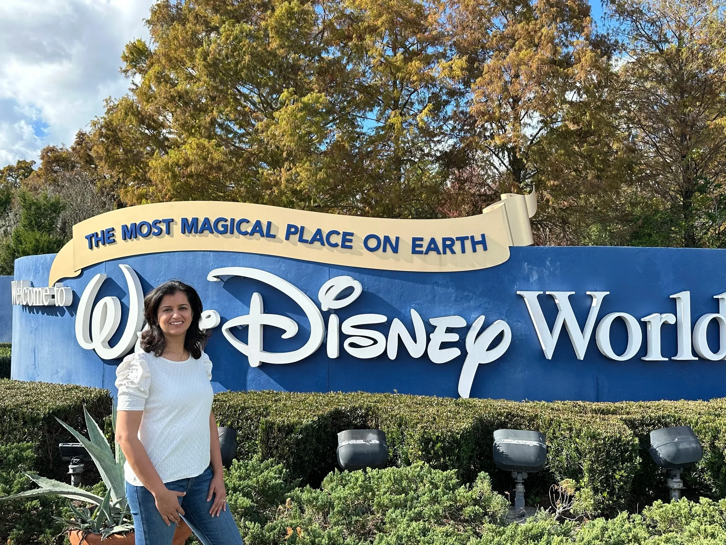 Dr. Rachita Bansal standing in front of a Disney World sign with trees in the background.