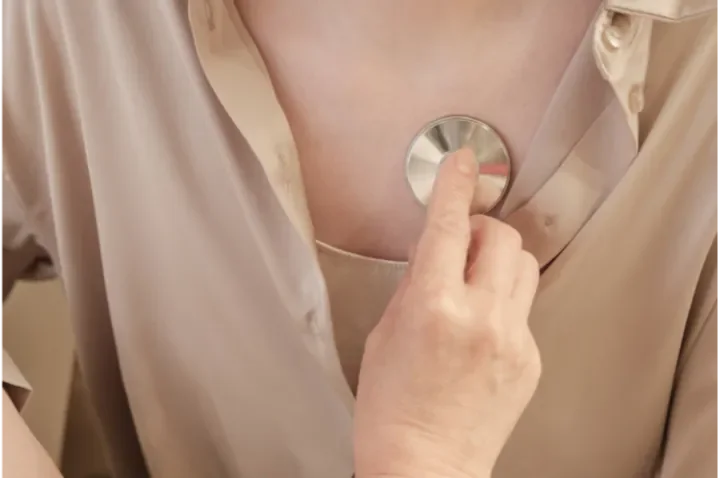 Person using a stethoscope on their chest.
