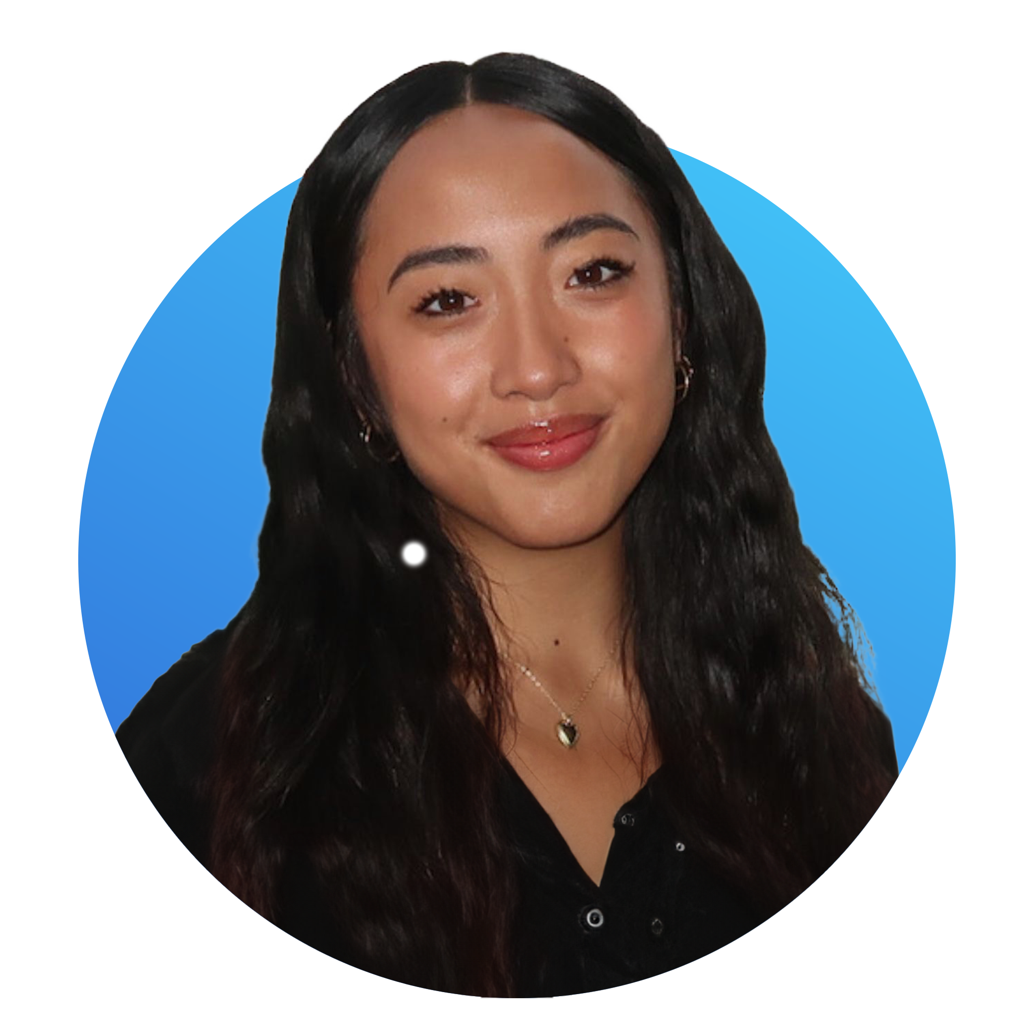 A woman with long wavy black hair, wearing a black top and a gold necklace with a heart-shaped pendant, smiling at the camera.