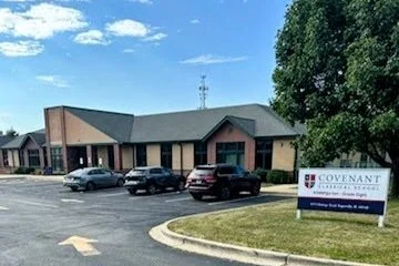 Covenant church building with cars parked in front and a sign on the lawn.