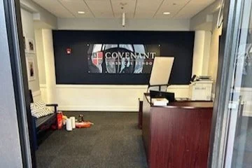 Office reception area with a sign that reads 'Covenant' on the wall behind a desk.