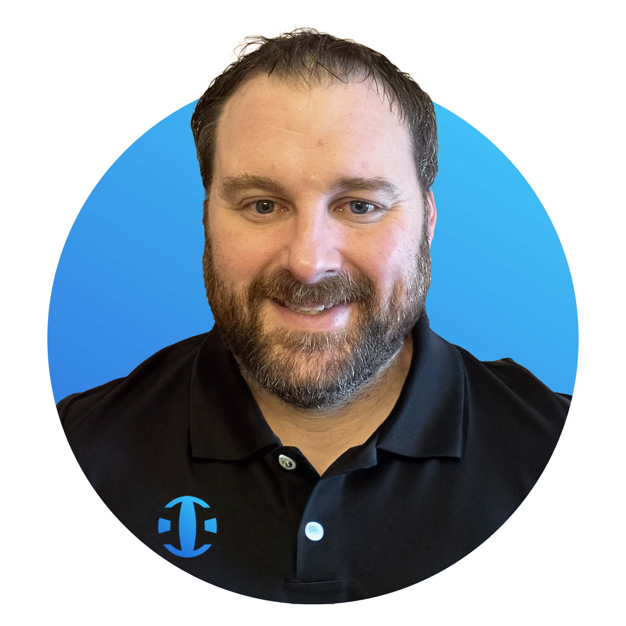 A man with a beard and short hair smiling, wearing a black collared shirt with a blue logo, against a background with shades of blue and tan.