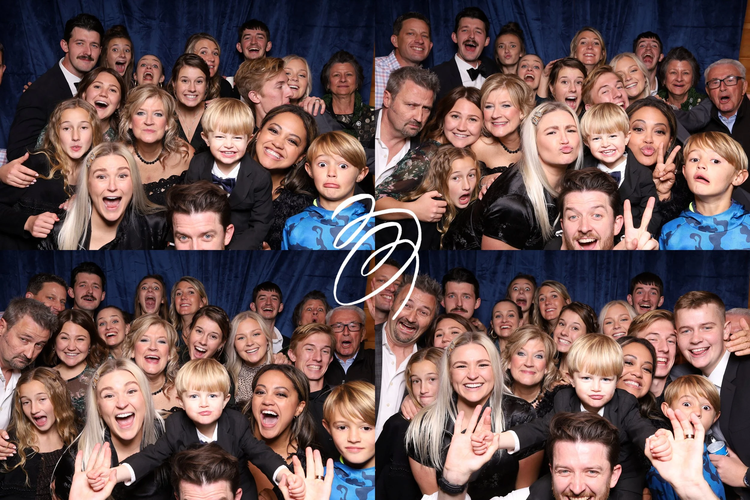 A large group of people, including children and adults, posing for a photo in front of a blue curtain at a celebration or event.