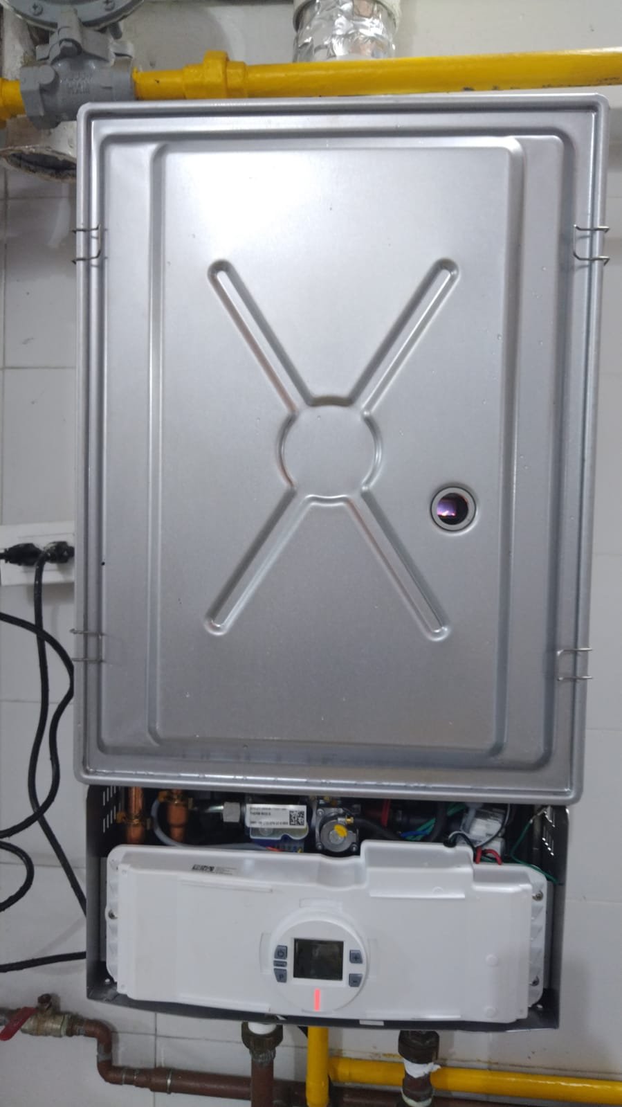 Equipo de fontanería y calderas instalado en una pared con tubos y componentes metálicos.