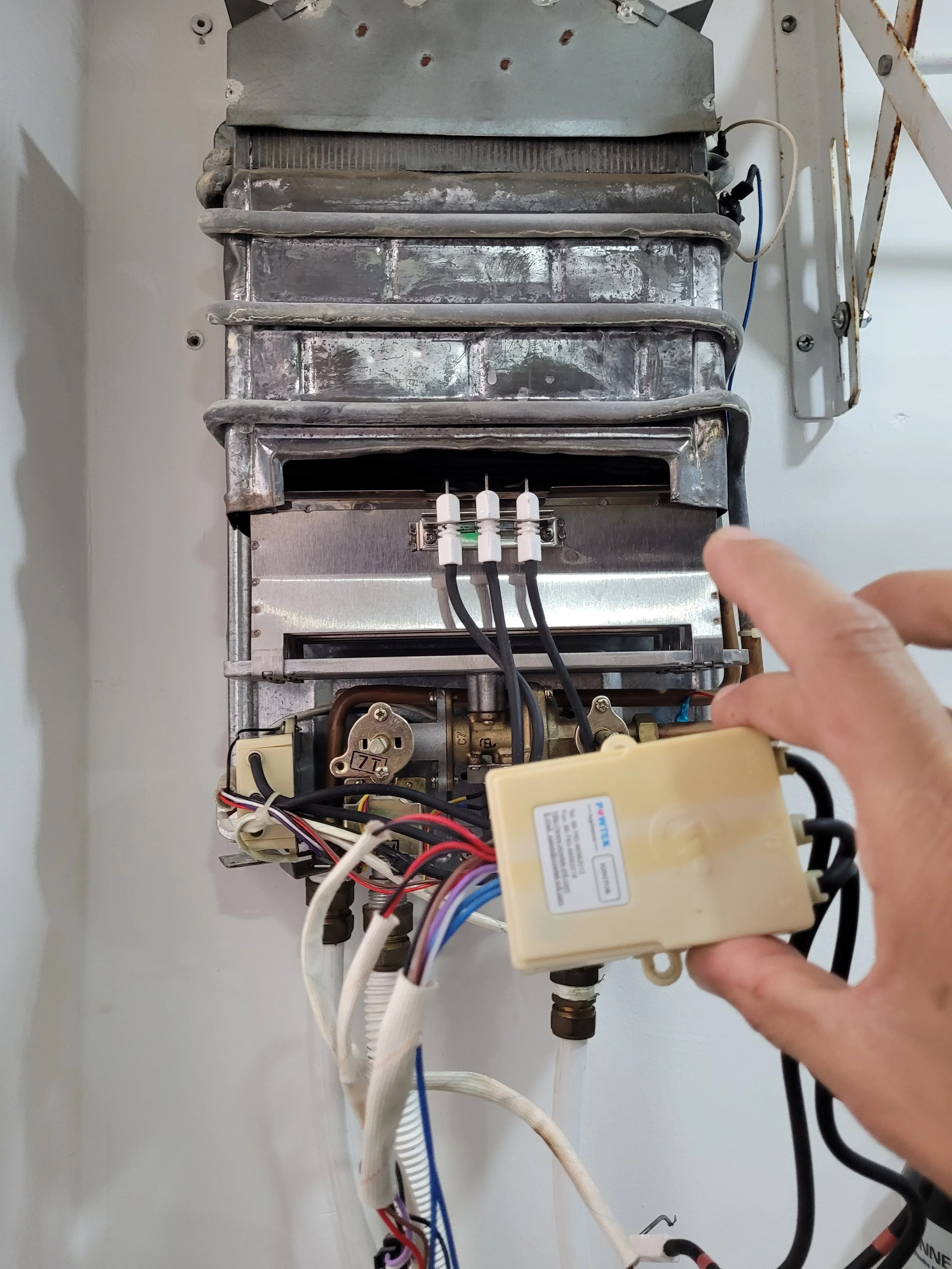 Imagen de un aire acondicionado con sus componentes internos visibles, incluyendo cables eléctricos y partes metálicas, siendo manipulado por una persona.