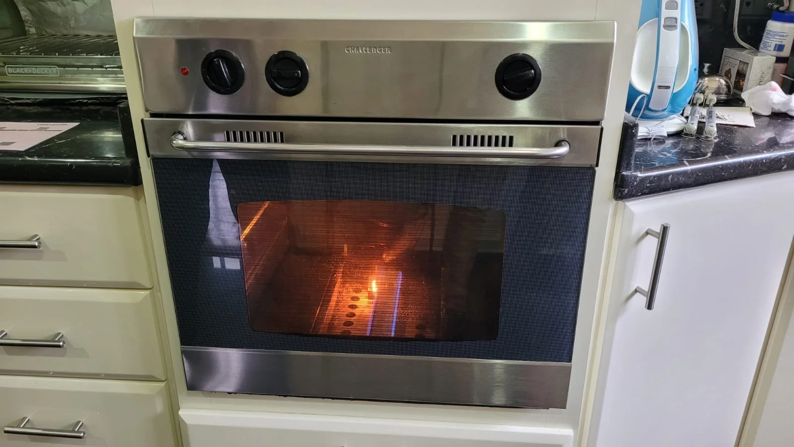 Estufa de horno de acero inoxidable en una cocina, con el horno encendido y visible a través del vidrio del horno.