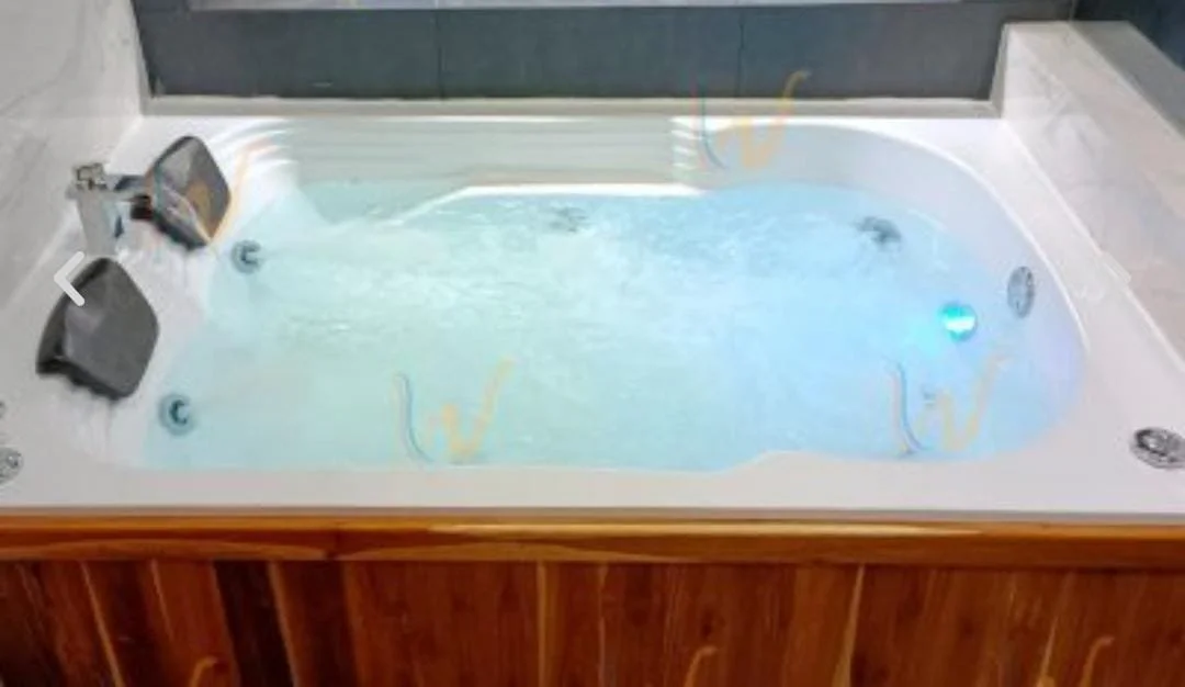 Jacuzzi con burbujas de agua en interior con paredes de azulejo y marco de madera.