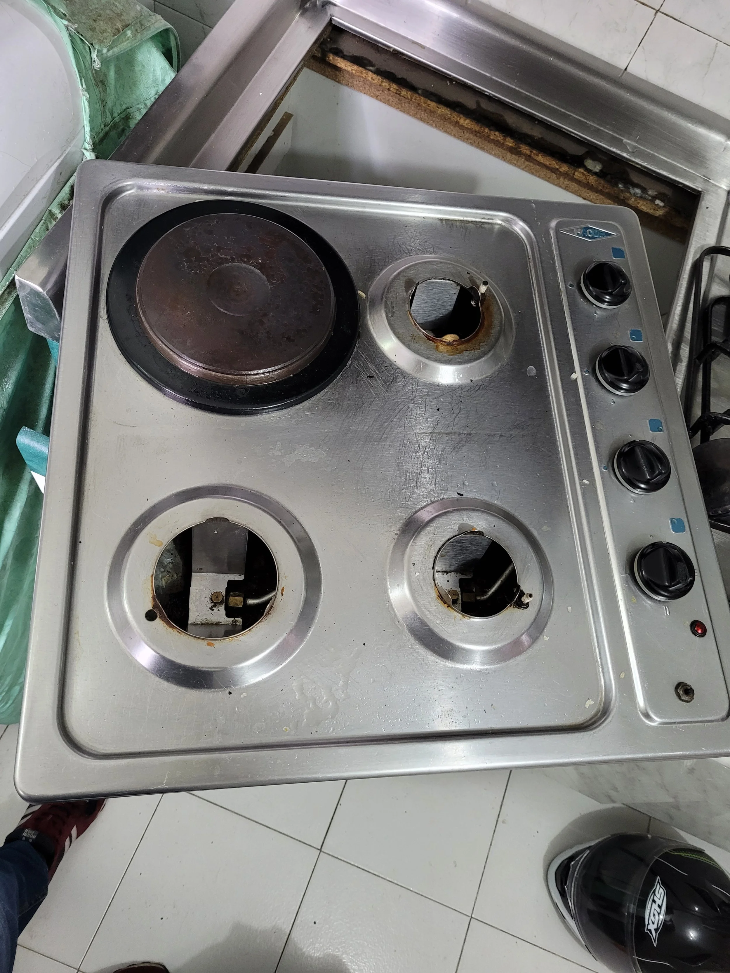 Cocina eléctrica dañada con quemadores rotos y arena debajo.