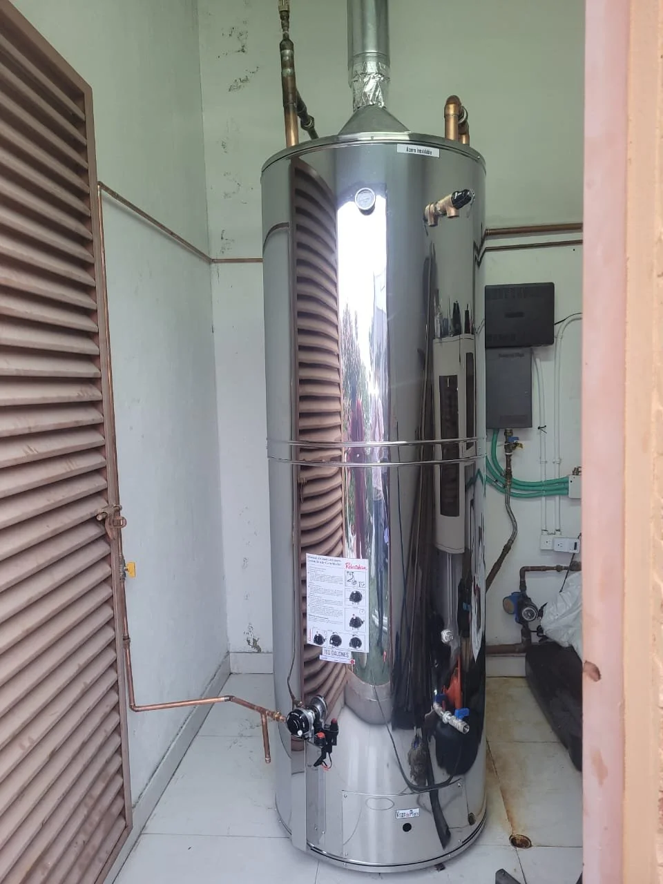 Calentador de agua de tanque de acero inoxidable en un cuarto de servicios.
