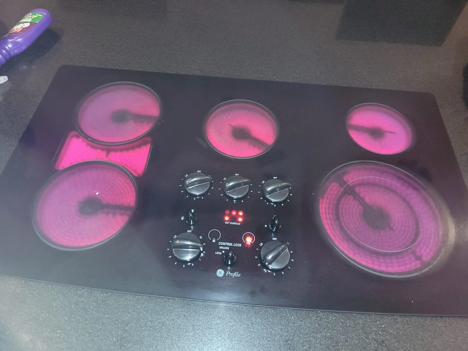 Estufa eléctrica con seis hornillas encendidas con luz rosa.