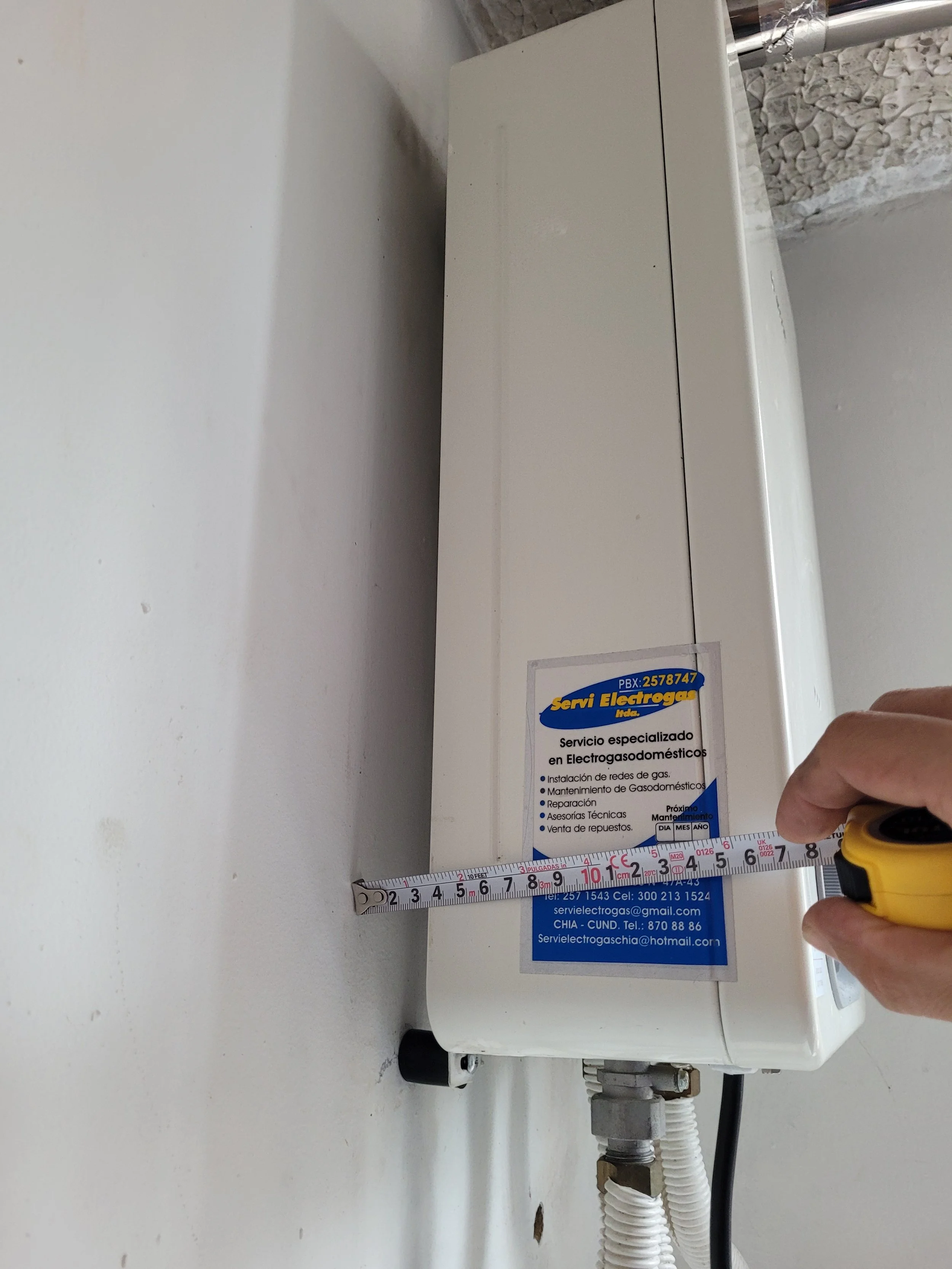 Persona midiendo la caja de un electrodoméstico con una cinta métrica.