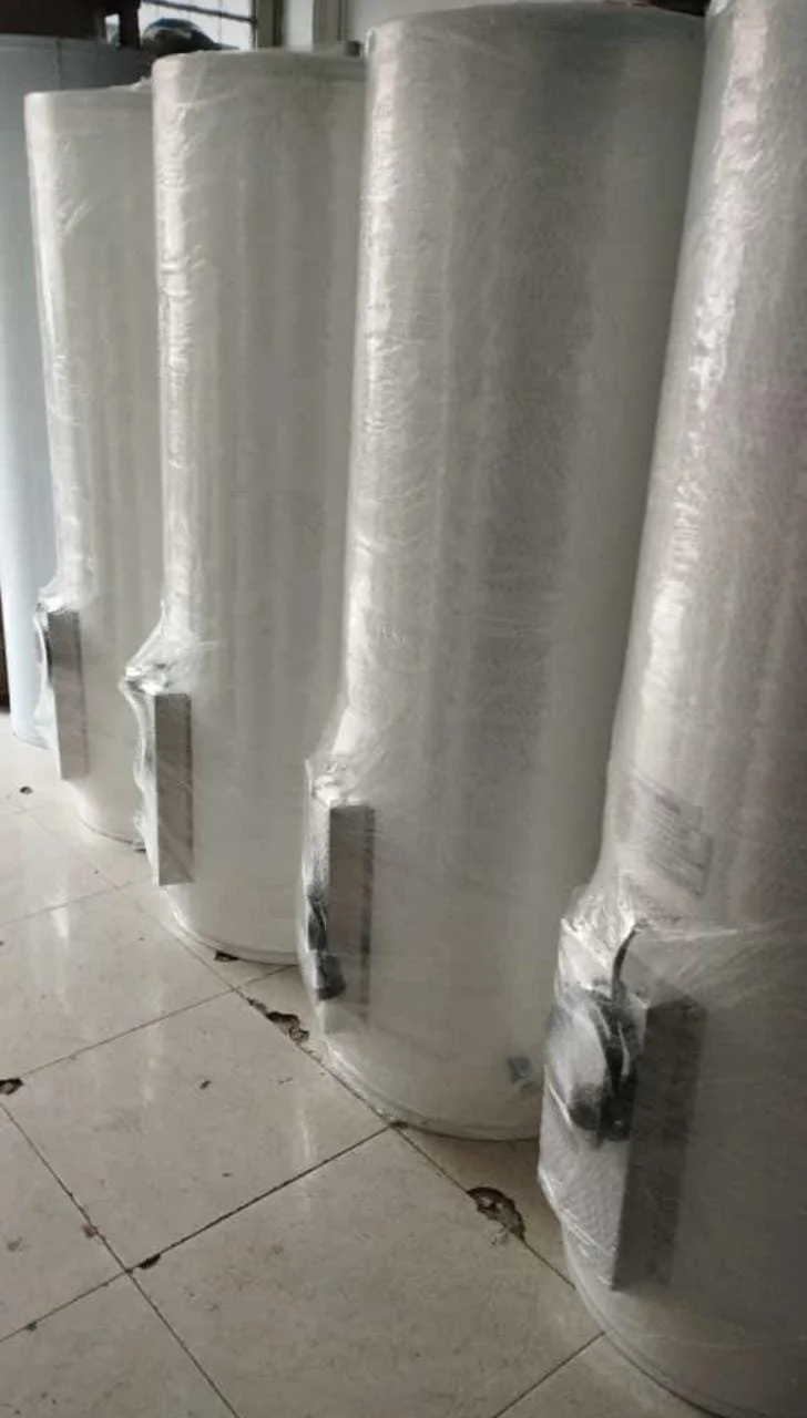 Seis tanques grandes de acero inoxidable envueltos en plástico de embalaje, colocados en piso de cerámica.