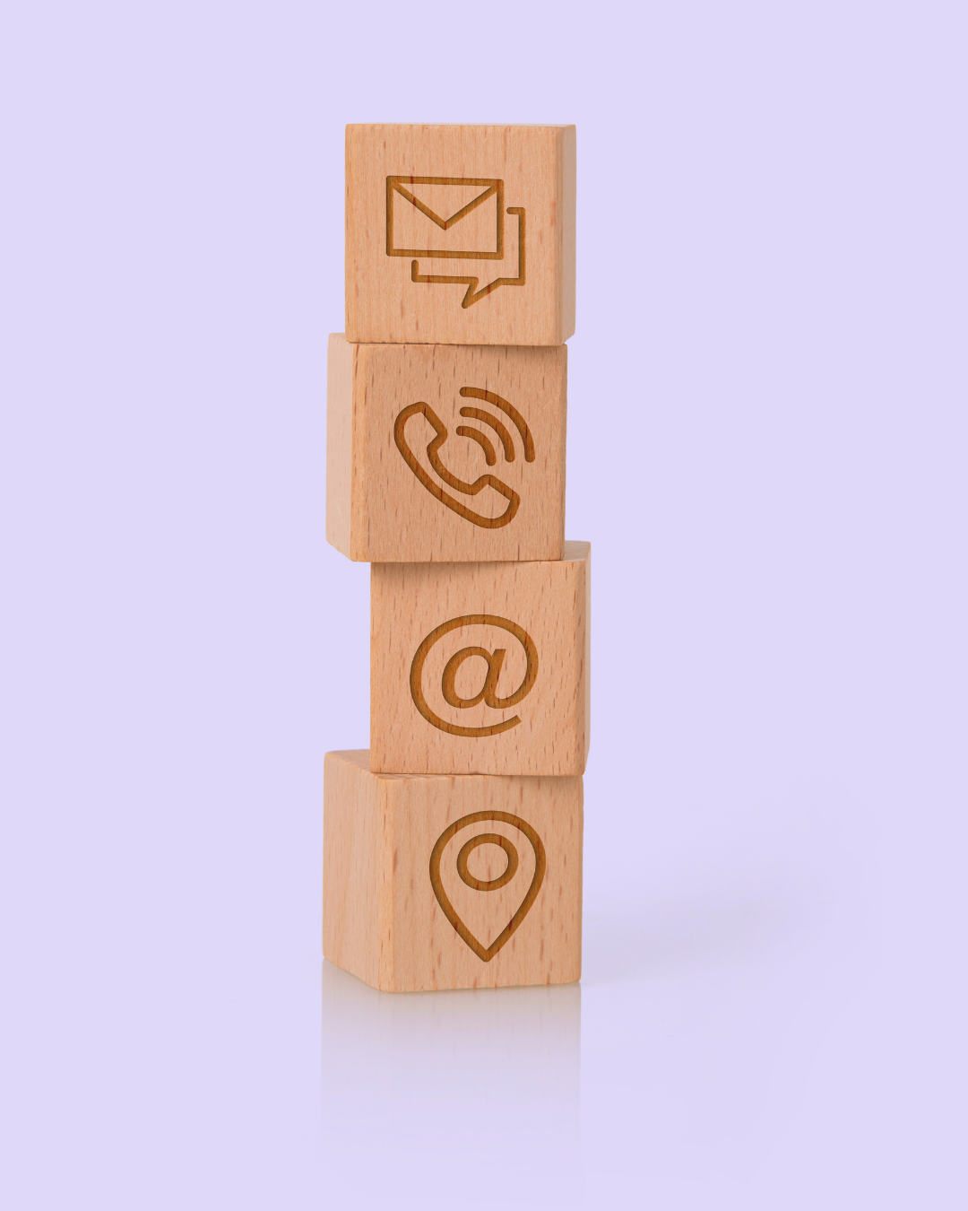 Four wooden blocks with engraved icons, including an email, phone, at symbol, and location marker, stacked vertically on a light purple background.