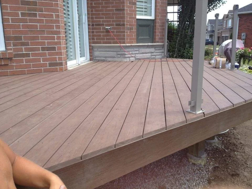A newly constructed wooden deck attached to a brick house.