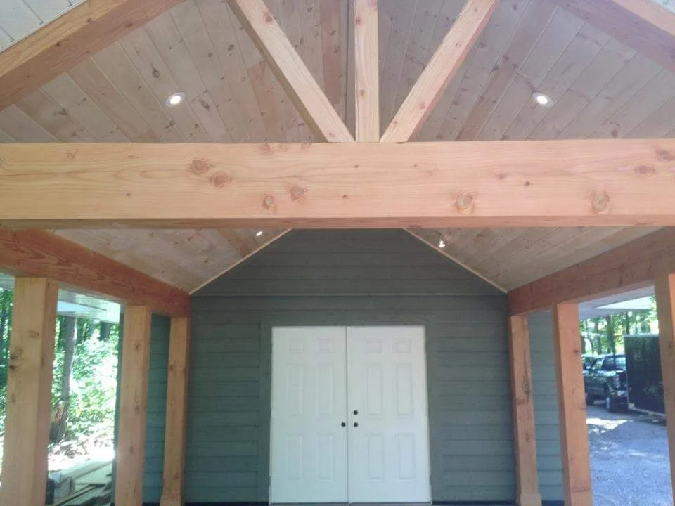 Wooden interior of a building with a vaulted ceiling and white double doors.