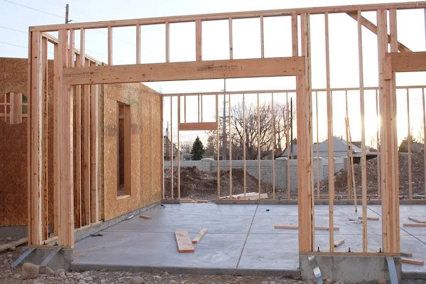 Wooden framing for a house under construction with concrete foundation and outdoor setting.