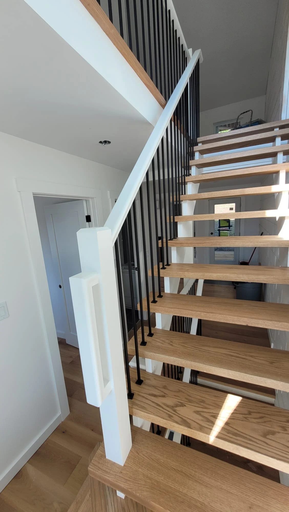 Interior view of a modern staircase with wooden steps and black metal balusters in a home.