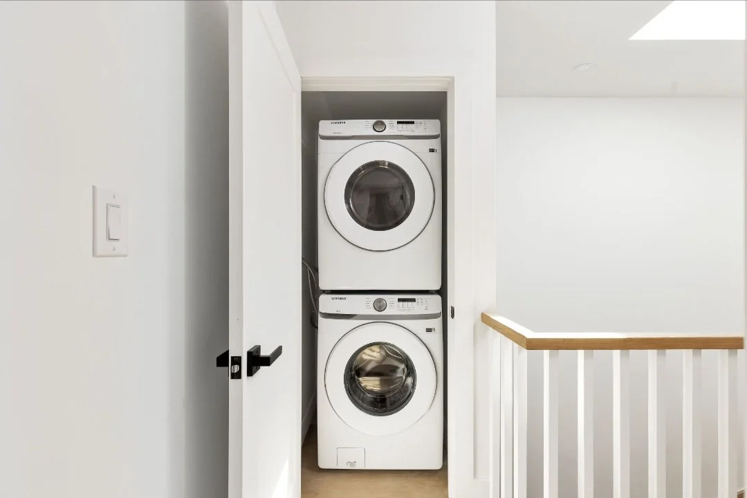 Stacked front-loading washing machine and dryer inside a closet with a white door
