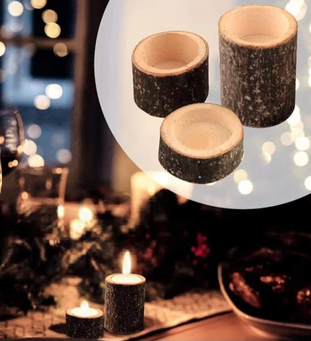 Three hollow log candle holders with one standing upright and two laying down, with a lit candle in the foreground, and blurred bokeh lights in the background.